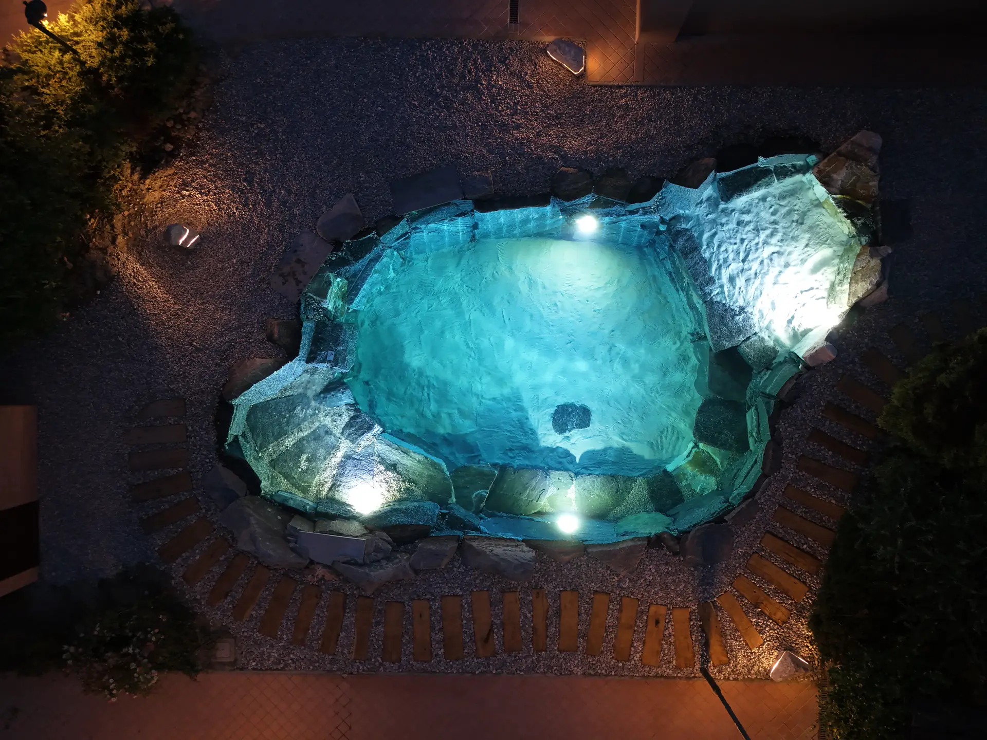Piscina naturale illuminata di notte, vista dall'alto