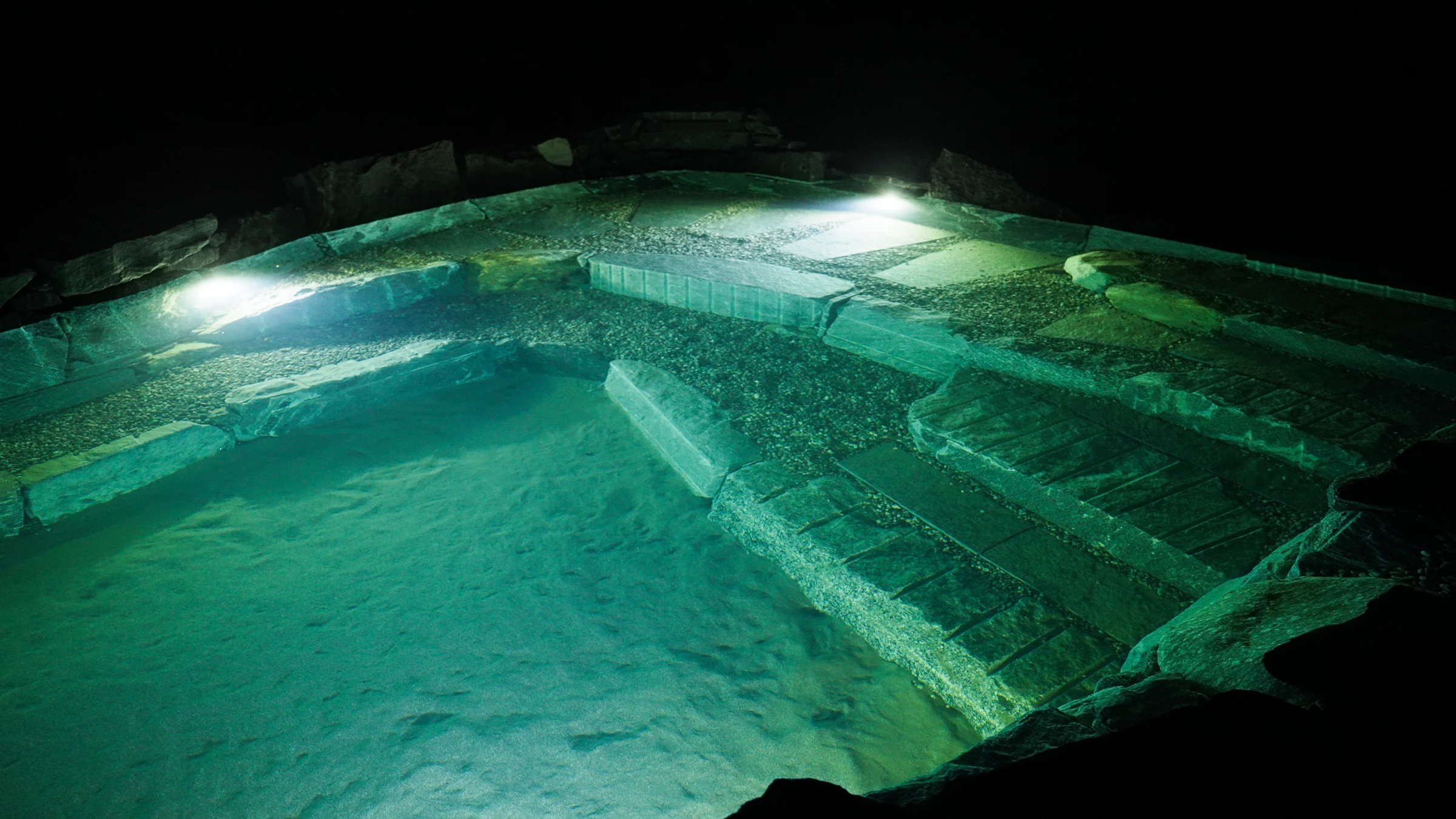 Piscina naturale illuminata di notte, vista dall'alto